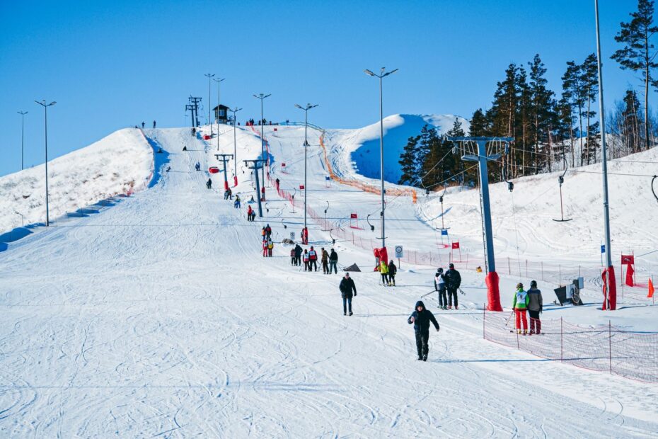 People enjoy a sunny winter day skiing and snowboarding at a bustling ski resort.